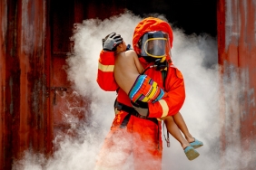 Firefighter, fireman helping injured boy to save him from burning warehouse