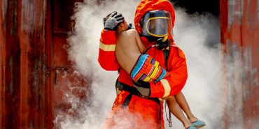 Firefighter, fireman helping injured boy to save him from burning warehouse